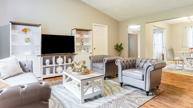A living room with a sofa, armchairs, a coffee table, a TV, and built-in shelving. - Walk to Dtwn Woodstock: Modern Home w/ Patio! (Woodstock)