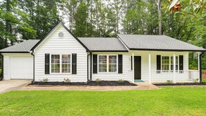 A single-story house with a white exterior, black shutters, and a small porch. - Walk to Dtwn Woodstock: Modern Home w/ Patio! (Woodstock)