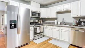 A modern kitchen with white cabinets, stainless steel appliances, and a granite countertop. - Walk to Dtwn Woodstock: Modern Home w/ Patio! (Woodstock)