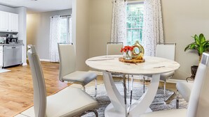 A dining area with a round table, four chairs, and a vase with flowers. - Walk to Dtwn Woodstock: Modern Home w/ Patio! (Woodstock)