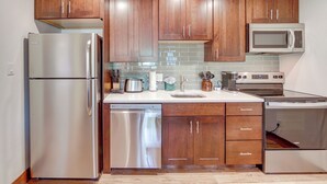 Une cuisine moderne dotée d’appareils électroménagers en acier inoxydable, de meubles en bois et d’un dosseret carrelé.