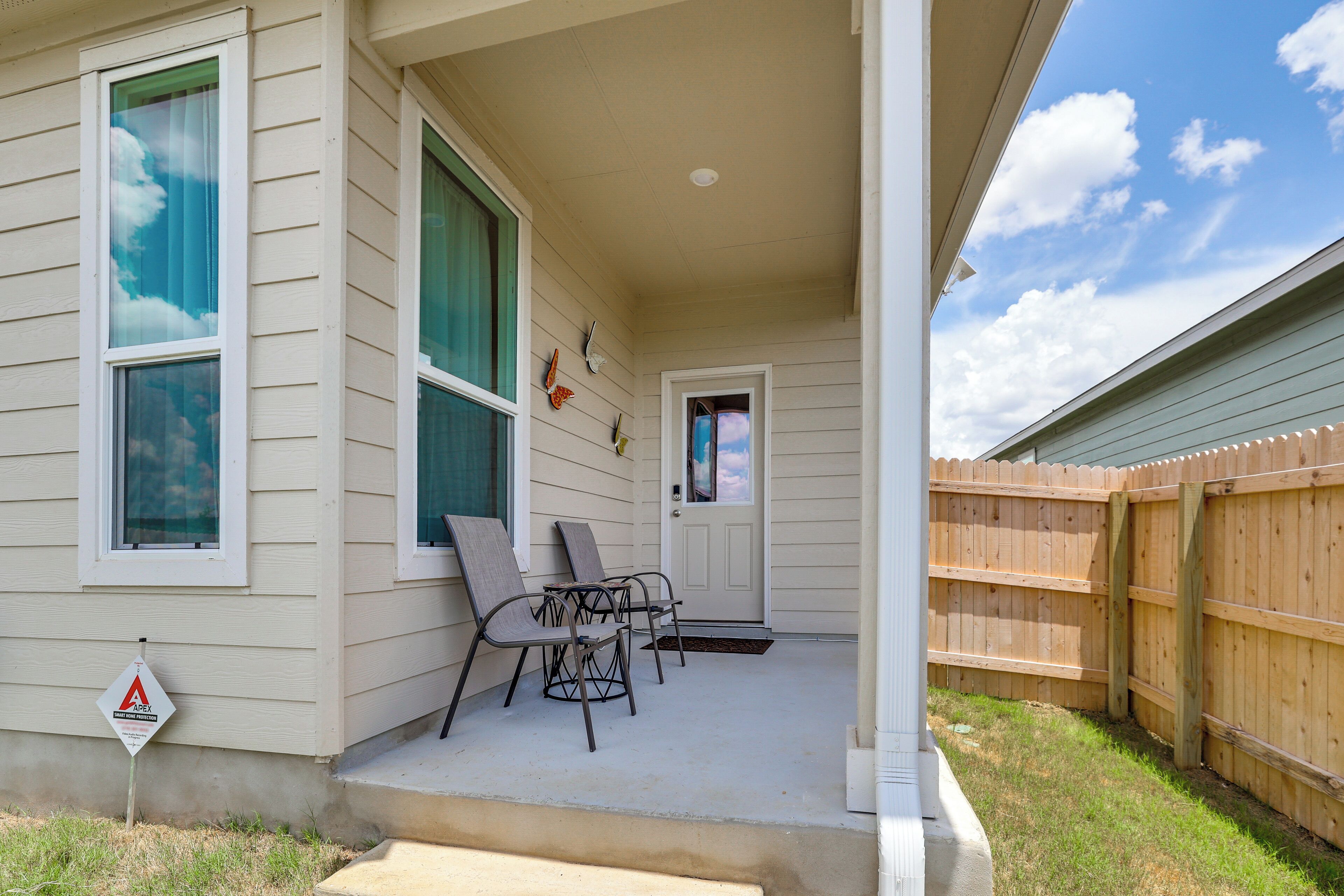 A house with a covered porch, two chairs, a small table, and a wooden fence.