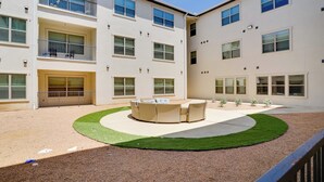 A courtyard with a circular seating area and a building with multiple balconies and windows. - King Bed Fort Worth Home Near I-35W & DFW! (Crowley)