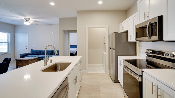 A modern kitchen with white cabinetry, stainless steel appliances, and a central island with a sink. - King Bed Fort Worth Home Near I-35W & DFW! (Crowley)