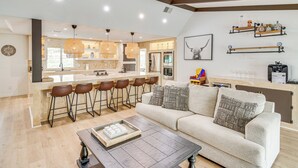 Eine moderne Küche mit Bar, Esstisch und Wohnbereich mit Sofa und Couchtisch.
