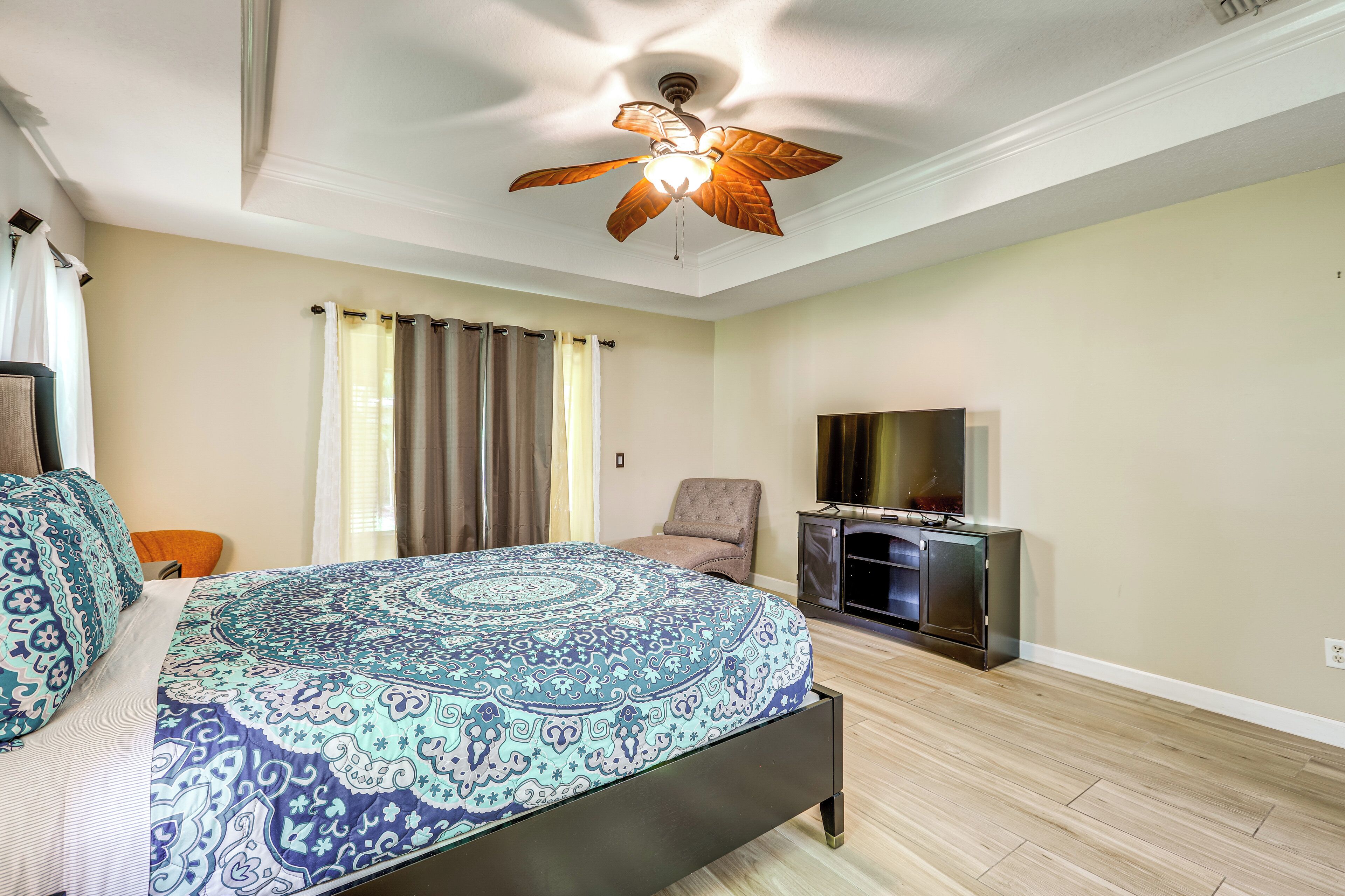 Un dormitorio con cama, ventilador de techo, televisión y chimenea.