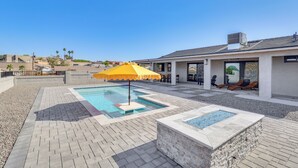 A rooftop pool area with a yellow umbrella, lounge chairs, and a modern building in the background. - 2 Mi to Windsor Beach! Updated, Sleek Family Home (Lake Havasu City)