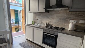 A modern kitchen with a gas stove, oven, and white cabinetry. - From Faith to the Sea Within walking distance of the sea, station and city center (Moneglia)