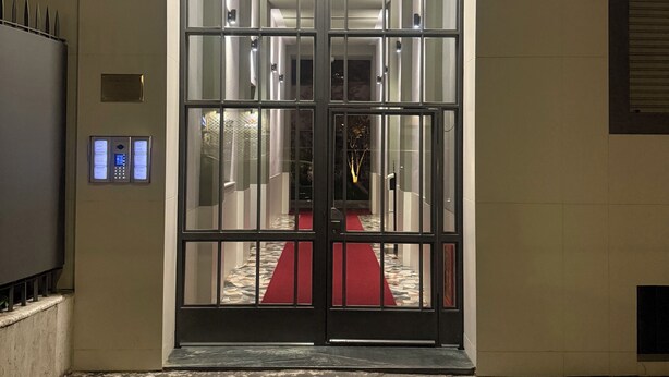 A hotel entrance with a glass door, a red carpet, and a number sign '39' on the wall.