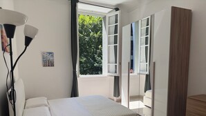 A bedroom with a bed, a desk, a lamp, and a wardrobe.