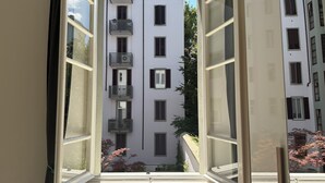 A view through an open window of a multi-story building with balconies and windows.