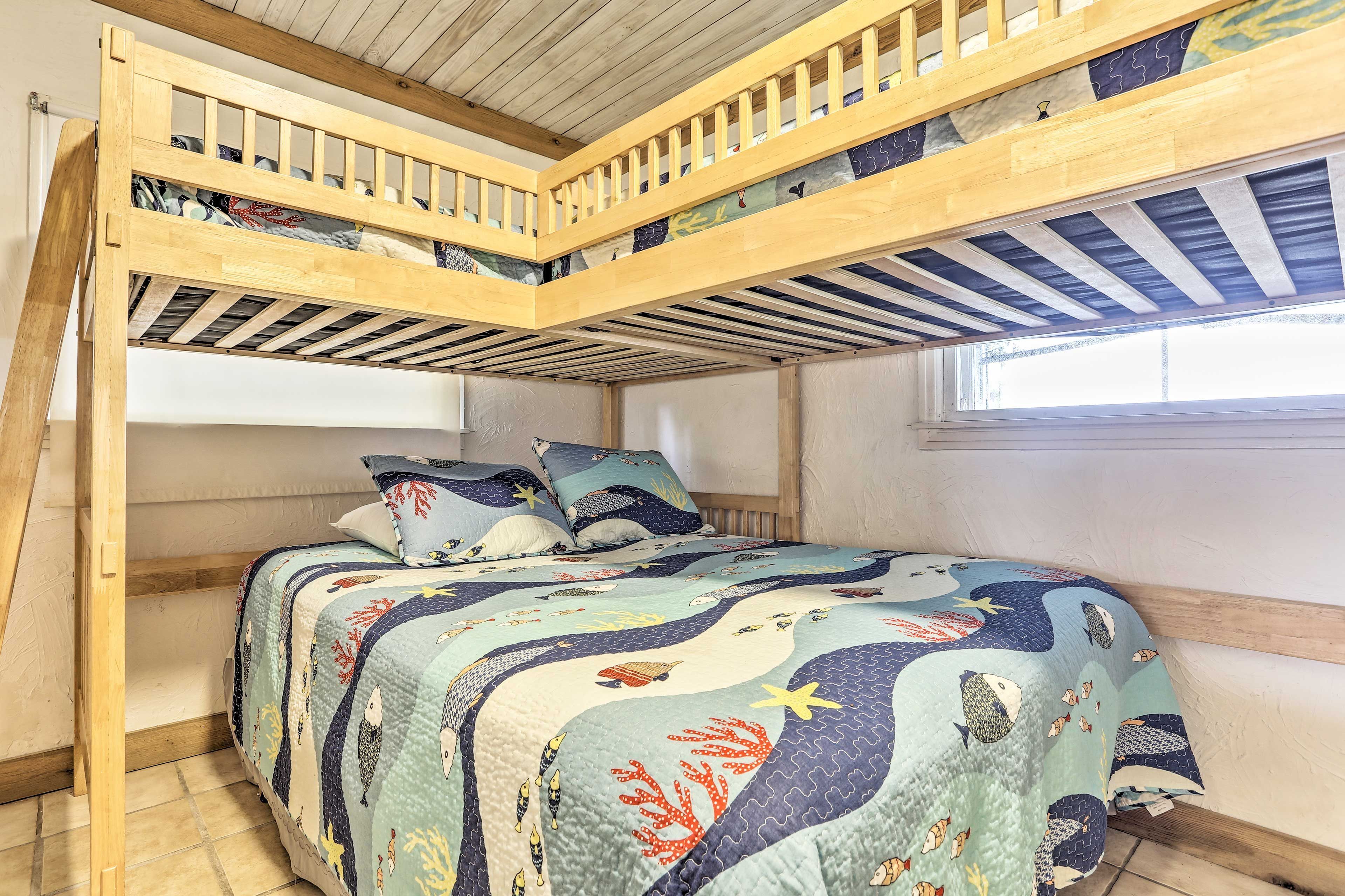 A bunk bed room with a wooden ceiling and a quilted bedspread.