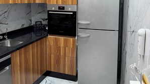 Une cuisine moderne avec des meubles en bois, un réfrigérateur en acier inoxydable, un four Bosch et un pare-feu en marbre.