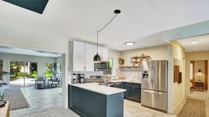 Una cocina moderna con una isla central, electrodomésticos de acero inoxidable y un comedor con vistas al exterior.