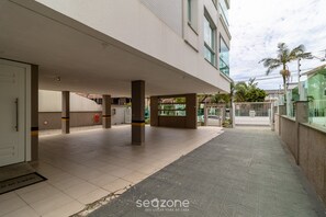 A covered outdoor area with a tiled floor, pillars, and a gated entrance.