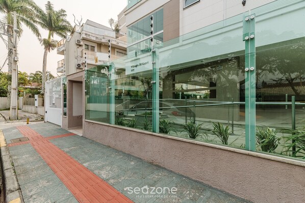 A modern building with a glass facade, a red pathway, and a sign reading "Viale Di Caprio 117".