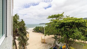 A beach view from a window overlooking a sandy beach with a playground and a slide, and a clear sky above. - Apartment Front to the Sea With Barbecue Vdr0202 (Florianópolis)