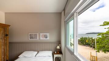 Un dormitorio con una cama, una mesita de noche, un armario de madera y dos cuadros enmarcados en la pared.