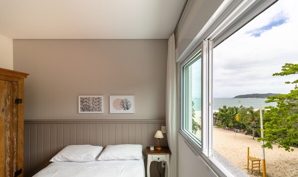 A bedroom with a bed, a nightstand, a wooden wardrobe, and two framed pictures on the wall.