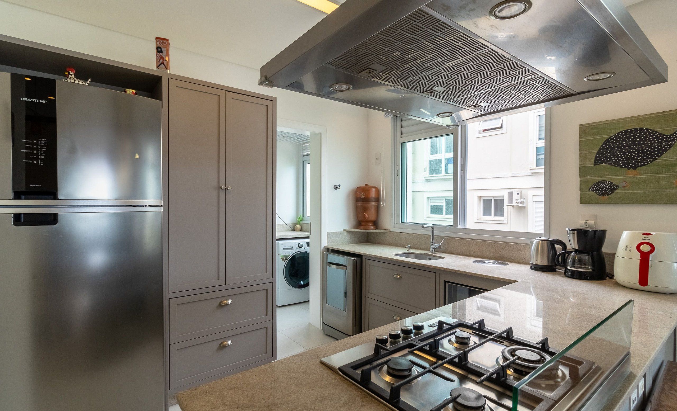 A modern kitchen with stainless steel appliances, a gas stove, and a large window providing natural light.