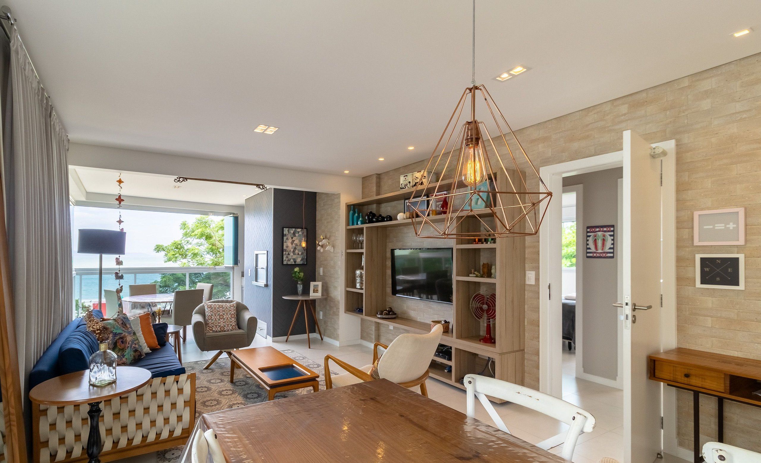A modern living room with a wooden dining table, comfortable seating, a TV, and a bookshelf.