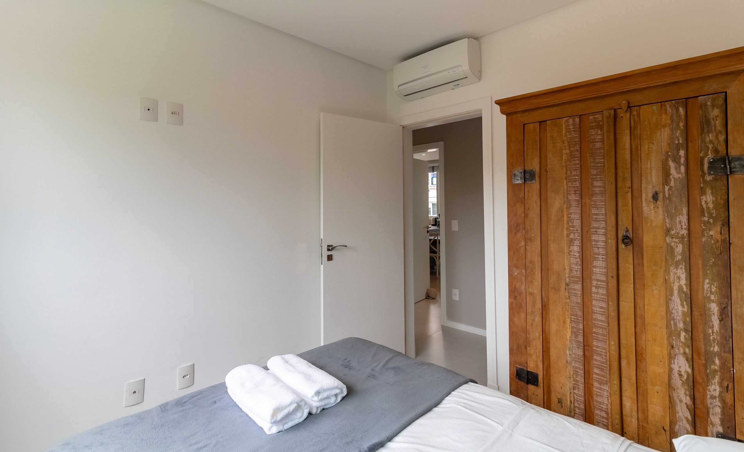 Un dormitorio con cama, armario de madera y unidad de aire acondicionado.