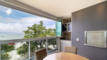 Habitación moderna con un ventanal grande con vistas a una playa, una mesa redonda y una pared con motivo de espiga.