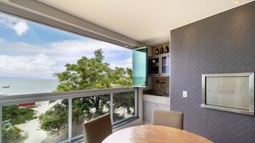 A modern room with a large window overlooking a beach, a round table, and a herringbone-patterned wall.