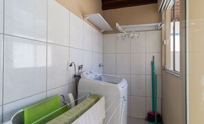 Ein Badezimmer mit Waschmaschine, Wäscheständer und Besen.