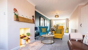 A modern living room with a sofa, a yellow armchair, a coffee table, and a fireplace with decorative items. - A  cosy place to stay near Manchester Airport (Heald Green)