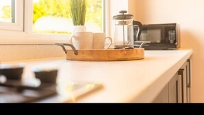 A kitchen counter with a coffee maker, a pot, and a window with a view of greenery. - A  cosy place to stay near Manchester Airport (Heald Green)