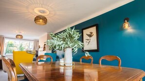 A dining area with a wooden table, chairs, a vase with a plant, and a framed picture on the wall. - A  cosy place to stay near Manchester Airport (Heald Green)