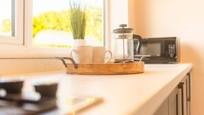 Een keukentrap met een koffiezetapparaat, een pan en een raam met uitzicht op groen.