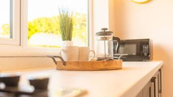 A kitchen counter with a coffee maker, a pot, and a window with a view of greenery.