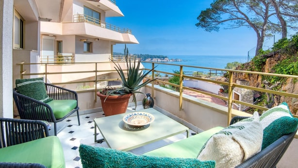 A balcony with a table, chairs, and a potted plant.