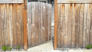 Una verja de madera con el número 13, que da a una casa de fachada gris y un pequeño porche.