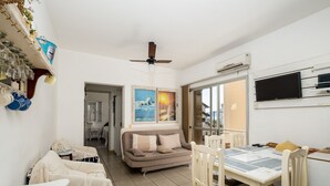 A cozy living area with a sofa, chairs, a dining table, and a ceiling fan. - Beautiful Apartments in Canasvieiras - VDM (Florianópolis)