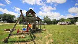 A playground with a swing set and a small wooden structure. - River Valley Campground (Wadena)