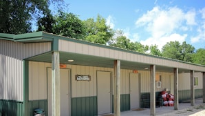 A row of cabins with green trim and a covered walkway. - River Valley Campground (Wadena)