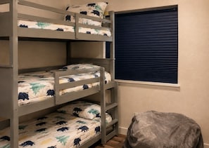 Una cama individual con ventana y una silla cubierta.