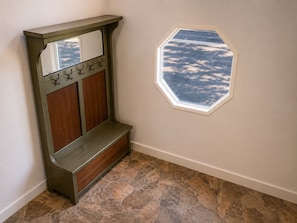 Un rincón con un banco de madera, un perchero y una ventana que da al cielo.