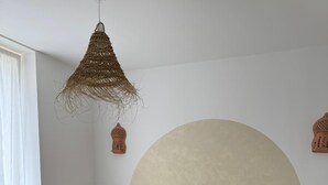 Een slaapkamer met een houten bedframe, wit beddengoed en een groot rond hoofdeinde.