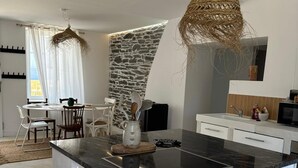 Een moderne keuken met een centraal eiland, witte kasten en een accentmuur van steen.