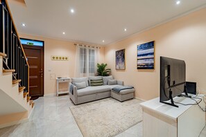 A modern living room with a sofa, a flat-screen TV, a small table, and a staircase. - Achada by Homie in Funchal (Funchal)