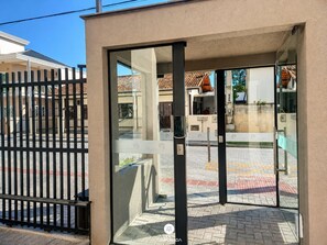 A gated entrance with a glass door, a metal gate, and a paved area with a tiled roof visible in the background.