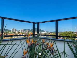 A balcony with a view of a cityscape, including buildings and mountains. - Skyline Comfort Club - Azul Celeste (Penha)