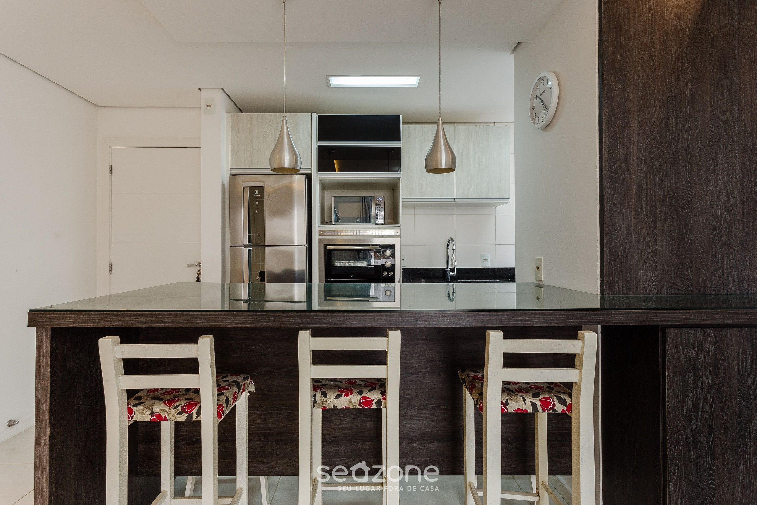 A modern kitchen with a central island, stainless steel appliances, and a clock on the wall.