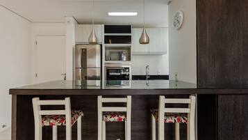 A modern kitchen with a central island, stainless steel appliances, and a clock on the wall.