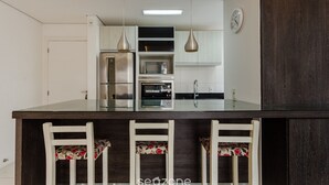 A modern kitchen with a central island, stainless steel appliances, and a clock on the wall. - Apt W/bbq, 850m From Ingleses Beach Vde101 (Florianópolis)