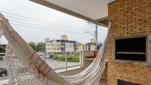 A hammock on a balcony with a brick wall and a fireplace. - Apt W/bbq, 850m From Ingleses Beach Vde101 (Florianópolis)